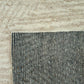 Close-up of a textured rug corner with a neutral color palette.