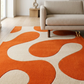 Orange and beige abstract patterned rug in a living room with a beige sofa.