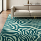 Living room with a patterned teal rug and beige sofa.