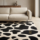 Modern living room with a cow print rug and a beige sofa.