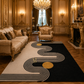 A large rectangular area rug with a bold black and cream wavy geometric pattern and two gold circles, styled in an ornate, luxurious gold-furnished living room.