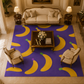 A large rectangular area rug with a purple background and bold yellow banana print, styled in a classic living room setting with a cream sofa, two armchairs, and a wooden coffee table.