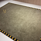 Gray mat with black and yellow striped border on a white surface