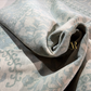 Roll of patterned fabric with a brand logo on a dark surface