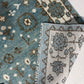 Close-up of a blue patterned rug with floral designs on a white floor.
