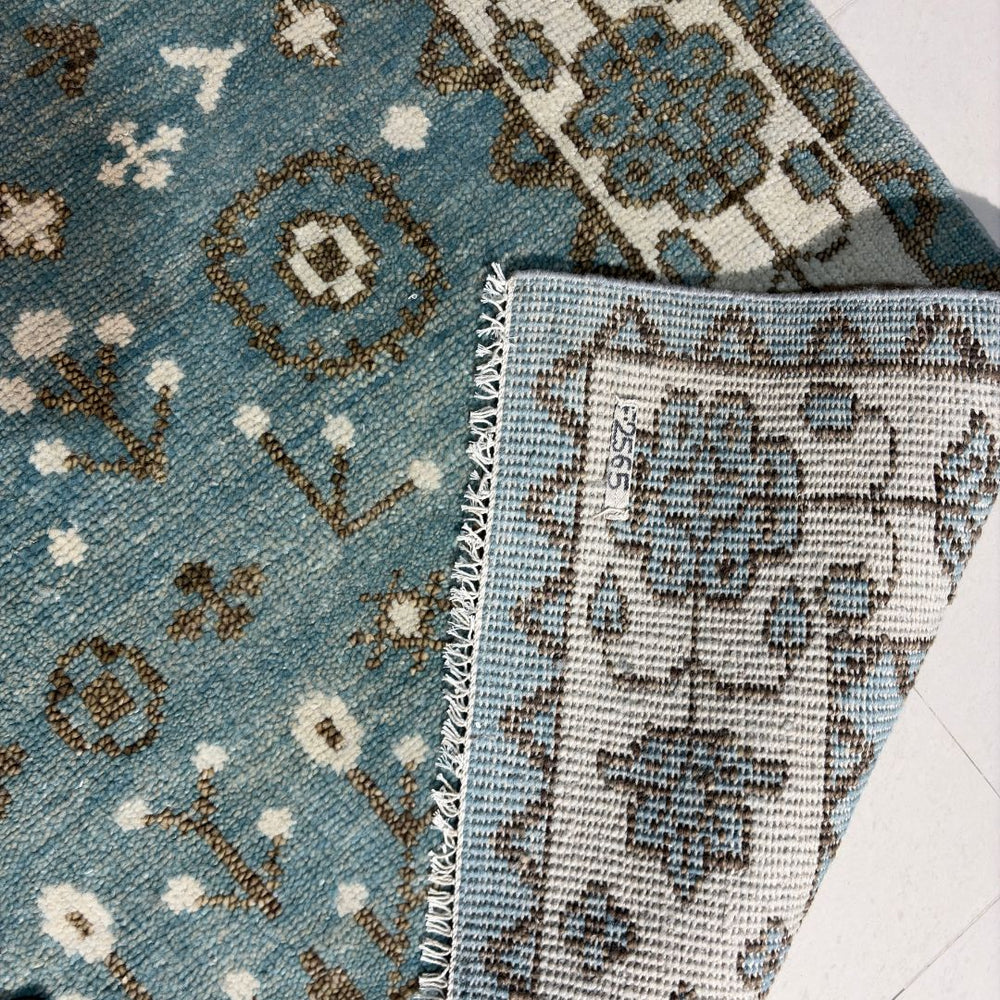 Close-up of a blue patterned rug with floral designs on a white floor.