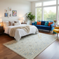 Modern bedroom with a bed, blue sofa, and large windows.