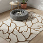 Patterned rug on a wooden floor with a pet bed and plant in the background.