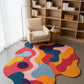 Colorful abstract rug in a room with a bookshelf and chair.