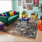 Colorful living room with a green sofa, colorful chairs, and abstract art on the wall.