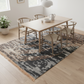 Dining area with a patterned rug, wooden table, and chairs in a bright room.