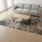 Gray sofa and wooden coffee table on a patterned rug in a room with large windows.
