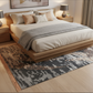 Bedroom with wooden bed, beige bedding, and patterned rug.