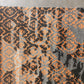 Patterned rug with orange and black design on a gray background