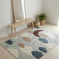 Children's room with a rug featuring cloud and moon designs, a wooden bench, and a mirror.