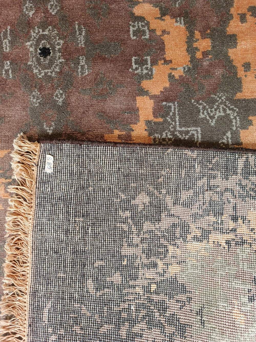 Close-up of a patterned rug with a visible brand label.