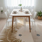 Dining room with a wooden table and white chairs on a patterned rug.