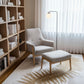Modern living room with a bookshelf, armchair, and ottoman.