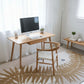 Home office with wooden desk, chair, and computer setup on a patterned rug.