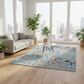 Living room with a colorful rug, gray sofa, and potted plants.
