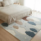 Bedroom with a cloud-patterned rug on a wooden floor