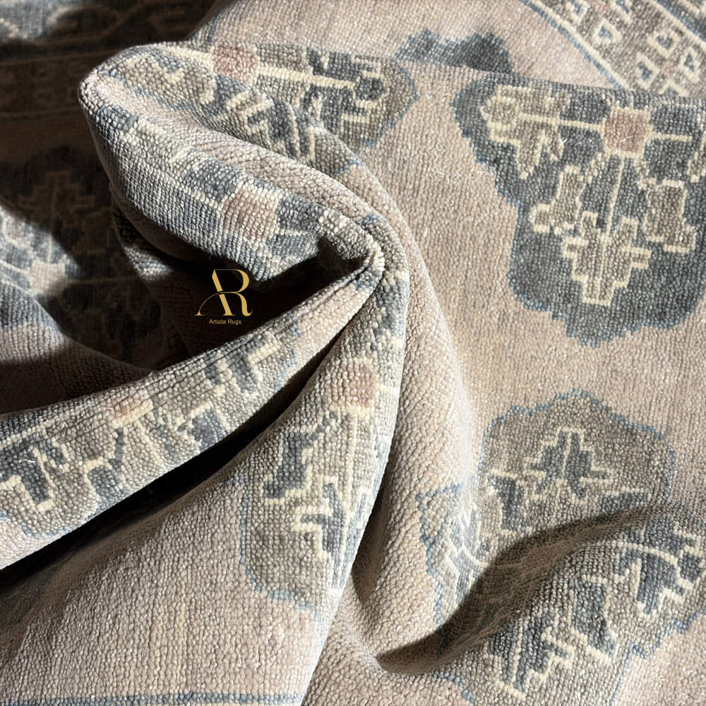 Close-up of patterned fabric with a brand logo, likely a rug or upholstery material.