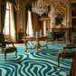 Luxurious room with ornate furniture, a chandelier, and a patterned rug.