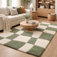 Living room with a checkered green and beige rug, beige sofa, and wooden coffee table.