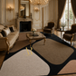 A large abstract area rug in beige, black, and blush pink tones is styled in an elegant, classic French chateau living room with gold-trimmed furniture and a fireplace.