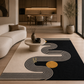 A modern area rug with a black base, cream wavy concentric lines, and a gold circle, styled in a contemporary living room next to a curved cream sofa.