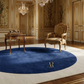 Luxurious room with ornate furniture and a blue rug featuring a logo.