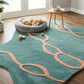 Teal rug with pink designs on a wooden floor, featuring a dog resting on a pet bed.