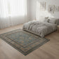 Bedroom with a patterned rug on wooden floor and white walls.
