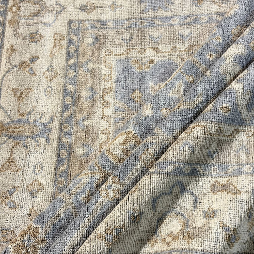Close-up of a textured rug with intricate patterns in blue, beige, and brown.