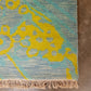 Close-up of a rug with yellow and blue pattern on a concrete floor.