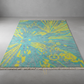 Teal and yellow patterned rug on a gray floor