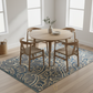 Dining area with a round wooden table and chairs on a patterned rug.