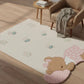Children's rug with teddy bear design on a wooden floor, next to a chair and small table.
