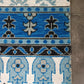 Close-up of a patterned rug with blue, black, and white colors on a textured surface.