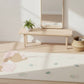 Children's room with a crib mattress featuring cartoon characters, a wooden bench, and a mirror.
