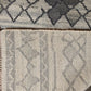 Close-up of a textured rug with geometric patterns in gray and beige.