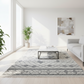 Modern living room with a patterned rug, coffee table, and abstract painting.