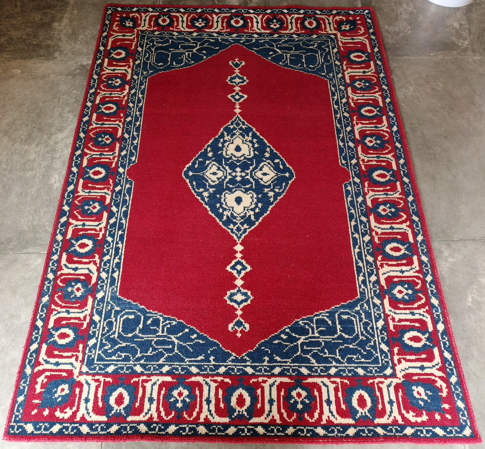 Decorative red, blue, and white rug on a concrete floor
