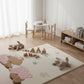 Children's playroom with a rug featuring teddy bear designs, toys, and a small table.