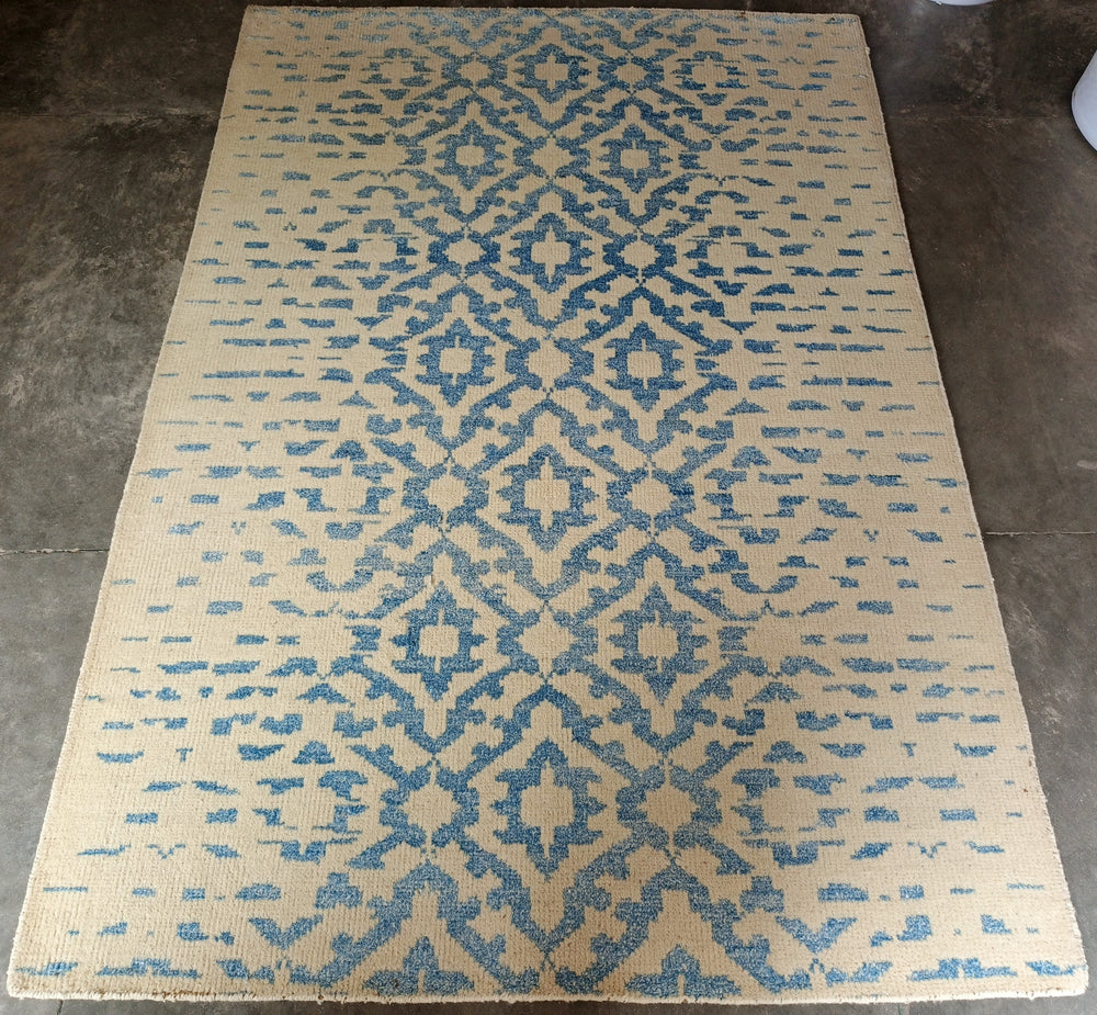 Beige and blue patterned rug on a concrete floor