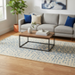 Living room with gray sofa, wooden coffee table, and patterned rug.