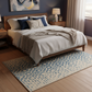Bedroom with wooden bed, white bedding, and a patterned rug.