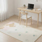 Room with a desk, chair, and rug featuring cartoon characters on a wooden floor.