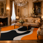 A large area rug with an abstract wavy pattern in black, white, and orange is styled in a luxurious, ornate vintage living room with gold furniture, a fireplace, and a chandelier.