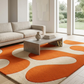 Modern living room with a beige sofa, coffee table, and orange and beige area rug.